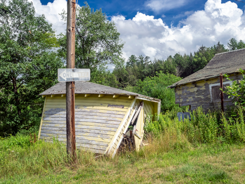 a dilapidated shed leaning over behing a telephone pole with a one way sign on it in Fillmore, MO
