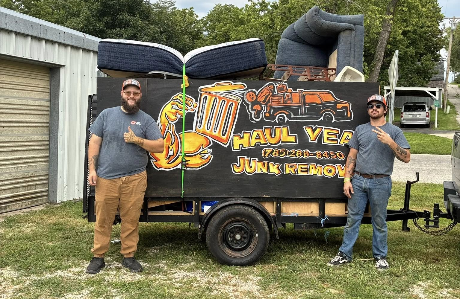 The owner of the company Cody Coppe and a team memeber standing on either side of a trailer with the Haul Yeah Logo and number painted on it in Hiawatha, KS and Surrounding Areas