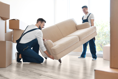 two movers lifting a couch together with some packed boxes around them in Fillmore, MO