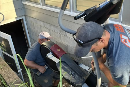 2 Haul Yeah Employees Carrying and excersize bike down a set of out door stairs into a house in Goff, KS